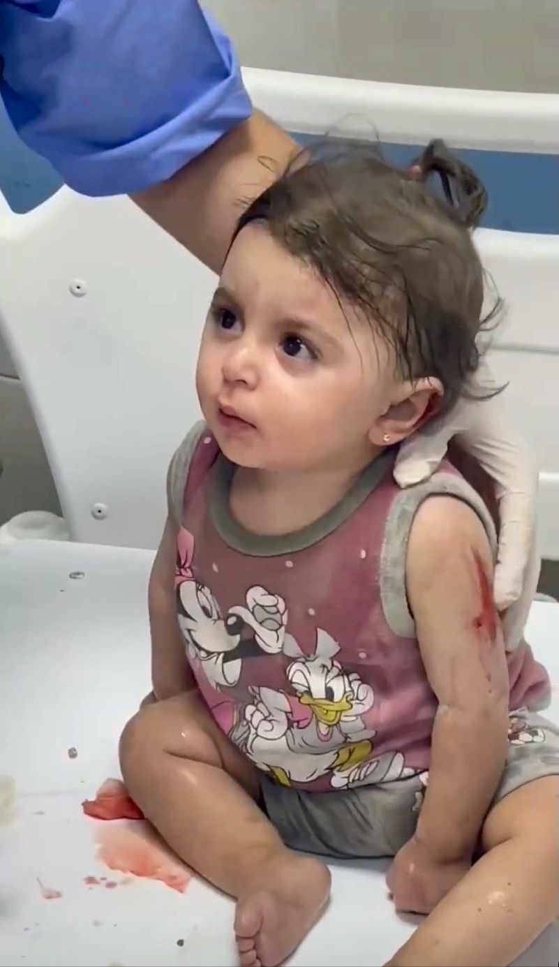 加沙废墟中幸存的小女孩，漂亮可爱，戴着耳钉，却害怕到忘了哭！