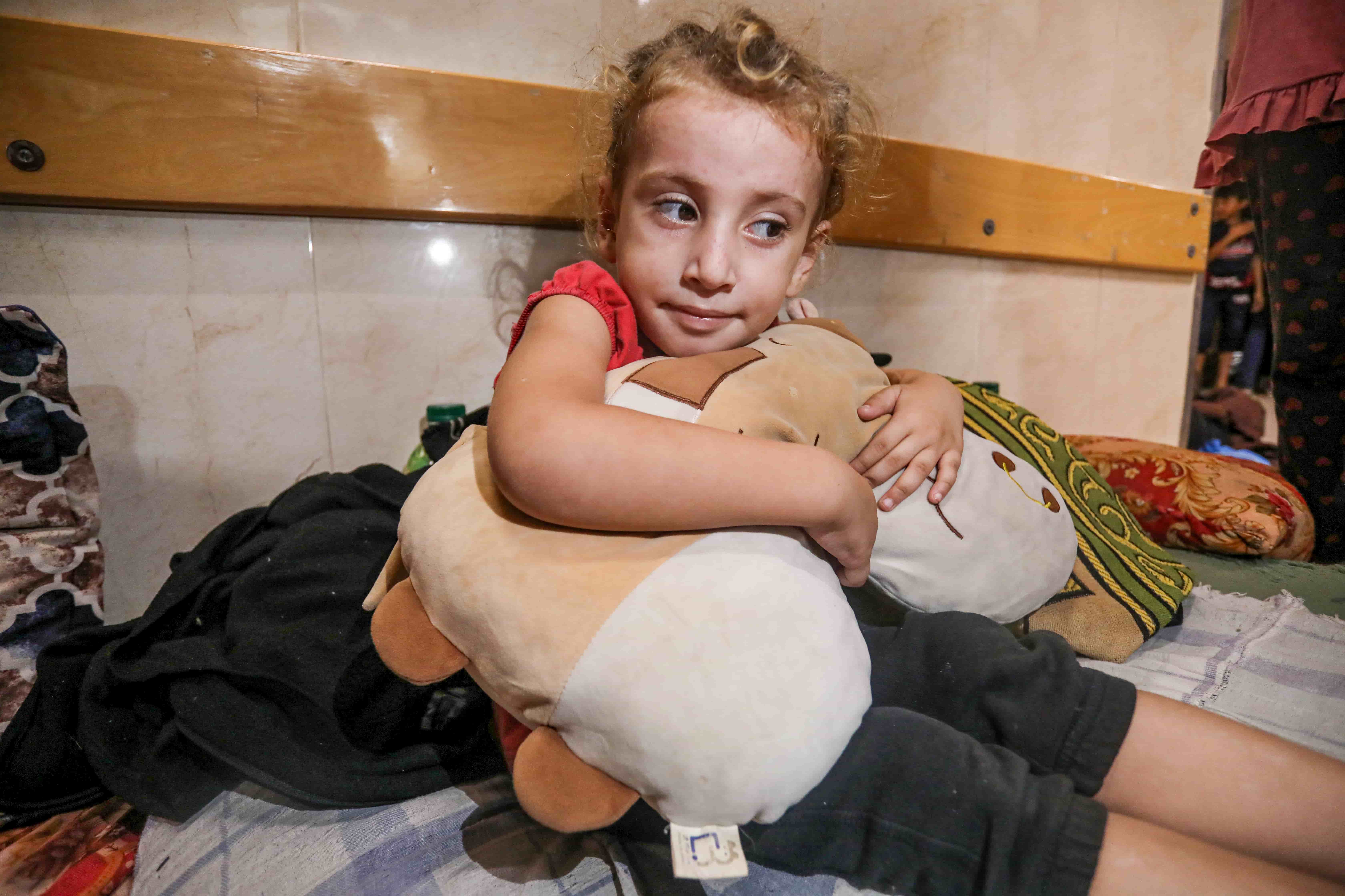 Ward Mouawed, 4, holds her favourite stuffed toy that she calls, Pillow. She says her home in Karama in Gaza City's north was destroyed in the Israeli bombing. [Abdelhakim Abu Riash/Al Jazeera]