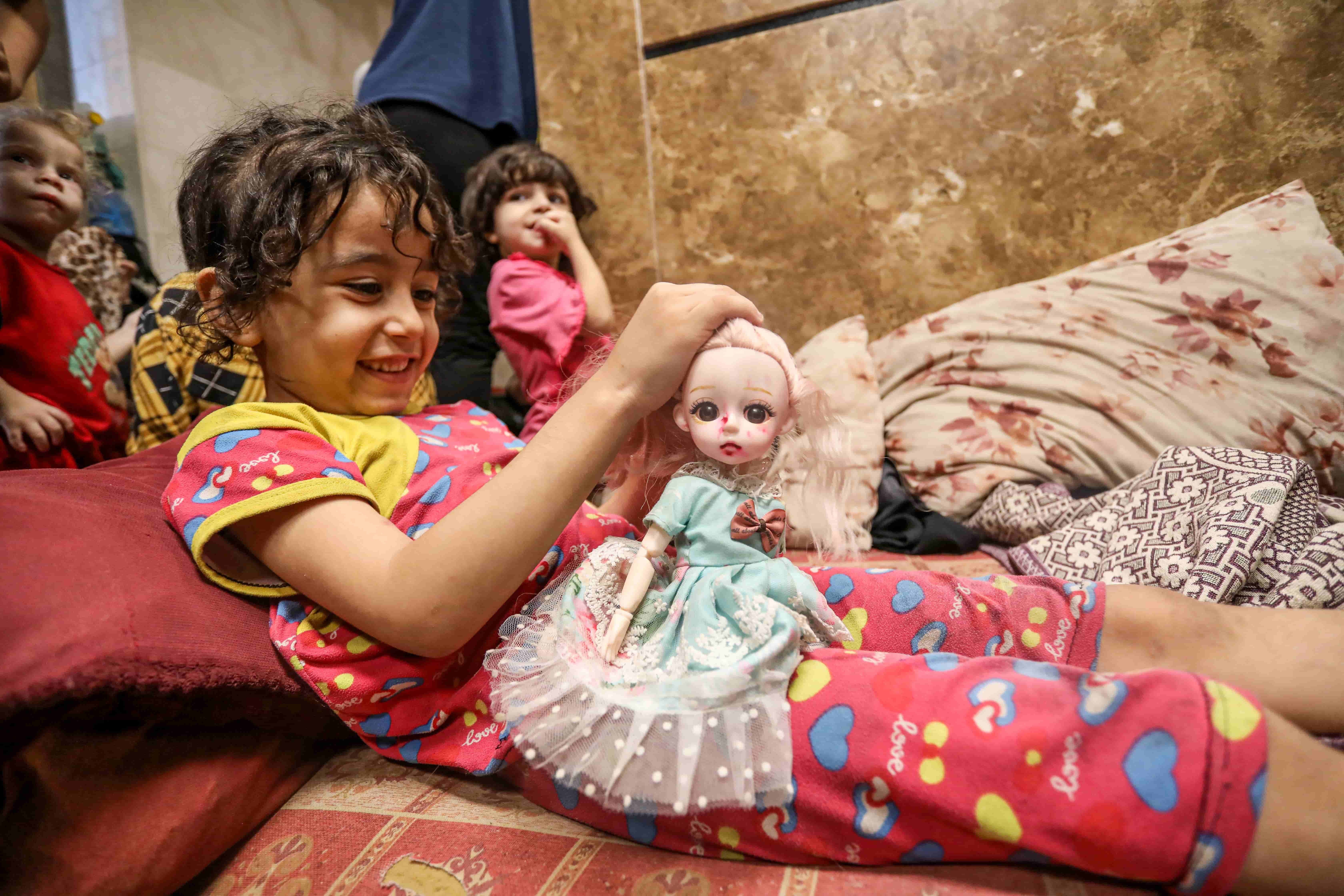 Farah Bakr, 5, rescued her doll from under the rubble of her home in the Shati (Beach) refugee camp as her family fled to the al-Shifa Hospital with other displaced families. [Abdelhakim Abu Riash/Al Jazeera]